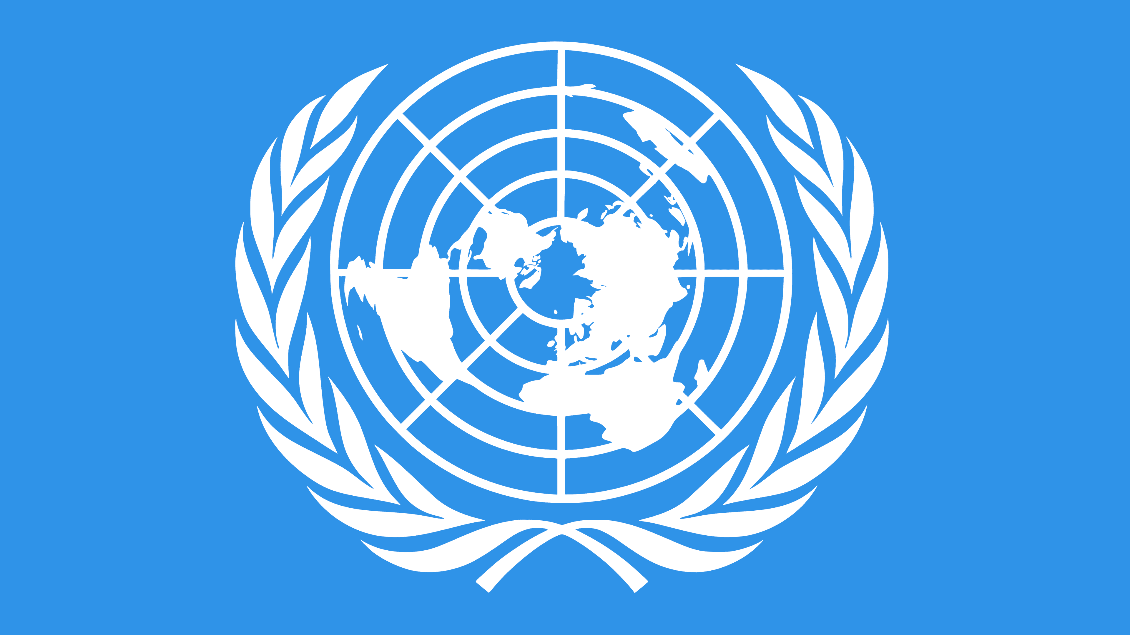 Logo Organizacji Narodów Zjednoczonych – biała grafika na błękitnym tle – pięć okręgów i mapa świata z biegunem północnym pośrodku. Wokół mapy biegną dwie gałązki oliwne. Logo symbolizuje misję ONZ: zapewnienie pokoju i bezpieczeństwa na całym świecie. 